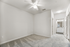 Bright and spacious bedroom with ceiling fan and plush carpet, featuring open doorway leading to an elegant bathroom with modern fixtures.