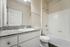 Elegant bathroom with granite countertop, sleek white cabinetry, and a pristine bathtub for a refreshing experience.