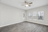 Bright living room with modern ceiling fan, elegant wooden flooring, and large windows offering abundant natural light.