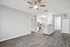 Bright modern apartment interior showcasing an open-concept kitchen with stainless steel appliances, wooden flooring, and a ceiling fan.