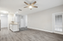 Modern open-concept apartment featuring sleek hardwood flooring, a ceiling fan, and a well-lit kitchen with granite countertops and white cabinetry.