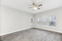 Bright and airy living room featuring elegant hardwood floors, a modern ceiling fan, and large windows for natural light.