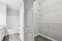 Spacious walk-in closet with modern shelving, adjacent to a sleek bathroom featuring elegant granite countertops and a pristine bathtub.