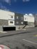 Modern apartment building with stone and dark panel accents under a clear blue sky.