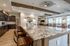 Luxurious open-concept kitchen and dining area featuring elegant granite countertops, rustic wooden beams, and modern cabinetry, perfectly lit by stylish ceiling lights.