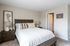 Inviting bedroom with a luxurious wooden bed frame, cozy white bedding, and elegant bedside lamps, creating a tranquil and stylish retreat.