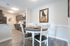 Charming apartment dining area with rustic wooden table, chic kitchen cabinetry, and captivating wall art.