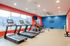 Modern apartment gym with sleek treadmills, vibrant red and blue walls, and expansive windows offering natural light.