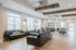 Bright and inviting communal space featuring modern leather sofas, large windows, and stylish wood accents for an atmosphere of comfort and elegance.