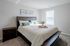 Inviting bedroom with a cozy king-size bed, elegant wooden headboard, and soft natural light streaming through large windows.