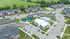 Aerial view of a modern apartment complex featuring spacious buildings, a sparkling swimming pool, vibrant playground, and ample parking surrounded by lush green landscapes.