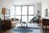 Bright, modern living room with stylish decor featuring a cozy sofa, chic armchair, and floor-to-ceiling windows offering abundant natural light.