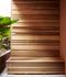 Contemporary wooden bench with slatted design surrounded by lush green plants, creating a serene and stylish outdoor living space.