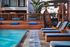 Luxurious poolside retreat with stylish wood accents, plush blue loungers, and lush tropical plants enhancing a serene ambiance.