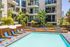 Luxurious apartment complex with a beautifully designed pool area, surrounded by lush greenery and modern balconies, perfect for relaxation and leisure.