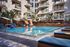 Luxurious apartment complex with a modern pool area, sun loungers, and lush greenery, offering a serene and stylish outdoor experience.