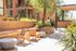 Charming outdoor patio with modern wooden seating, surrounded by lush greenery and a peaceful ambiance.