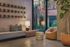 Chic modern living area featuring sleek gray sofa, stylish wooden accents, and vibrant greenery visible through large windows.