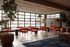 Chic and modern lounge area with vibrant orange seating, lush greenery, and floor-to-ceiling windows offering abundant natural light.