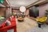 Inviting living space with vibrant red and green seating, modern fireplace, and chic round coffee table under a stylish pendant light.