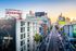 Vibrant cityscape view from an apartment at El Centro, featuring bustling streets, iconic billboards, and modern architecture against a sunset backdrop.