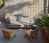Chic outdoor patio with modern wooden furniture and lush greenery, perfect for relaxing and enjoying the sun.