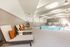 Luxurious indoor pool area with stylish lounge chairs and modern accents, perfect for relaxation and leisure.