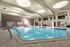 Luxurious indoor swimming pool with modern seating, natural light from circular skylights, and a serene atmosphere.