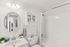 Elegant bathroom with modern fixtures, circular mirror, and sleek white tile design.