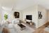 Elegant living room with modern decor, featuring a plush white sofa, abstract artwork, and a large flat-screen TV; perfect for stylish relaxation.