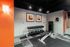 Chic apartment gym with a stylish weight bench, modern art, and vibrant orange accents.