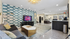 Contemporary lounge area with a modern sofa, stylish geometric wallpaper, and ambient lighting in a welcoming apartment.