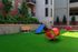 Vibrant Pet Park with lush green grass, a bright red tunnel slide, and playful blue climbing structure, creating a perfect urban oasis for your pet!
