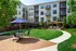 Charming apartment courtyard featuring lush green landscaping, cozy seating areas, and modern outdoor grills, perfect for relaxing and entertaining.