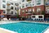 Modern apartment complex with a refreshing outdoor pool, surrounded by lounge chairs and stylish brick and siding architecture.