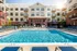 Luxurious apartment complex with a pristine outdoor pool, sunlit lounging chairs, and elegant balconies, perfect for a relaxing lifestyle.