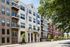 Elegant modern apartment building with charming balconies and lush greenery in a vibrant neighborhood.