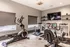 Modern home gym with sleek exercise bikes, elliptical machine, and wall-mounted TV, perfect for a stylish workout space.