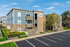 Charming apartment complex with modern architecture, featuring elegant stone facades, balconies, and lush landscaping under a bright blue sky.