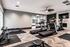 Modern fitness center with state-of-the-art treadmills, exercise bikes, and a set of free weights on sleek wood flooring, ideal for an active lifestyle.