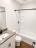 Elegant bathroom featuring a modern vanity, sleek countertop, and a pristine bathtub with contemporary fixtures.