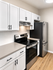 Modern kitchen with sleek stainless steel appliances, elegant white cabinetry, and a stylish wood floor.
