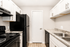 Modern kitchen with sleek black appliances, granite countertops, and stylish white cabinetry.