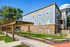 Charming residential building with rustic stone accents and a scenic wooden pergola walkway, nestled in lush greenery.