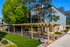 Charming apartment exterior with lush landscaping, elegant wooden pergola, and classic stone facade, promising a serene living environment.