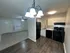 Inviting open-concept apartment with modern kitchen, sleek black appliances, and cozy carpeted living area.