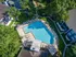 Aerial view of a stunning community pool area surrounded by lush greenery and modern apartments, offering a relaxing oasis.