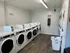 Modern laundry room with multiple washing machines, wooden flooring, and bright lighting, offering convenient in-building laundry services.