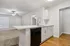 Modern open-concept kitchen with sleek white cabinetry, elegant countertops, and a cozy living area featuring a ceiling fan.