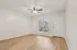 Bright and inviting room featuring elegant wood-style flooring, a modern ceiling fan, and a large window for ample natural light.